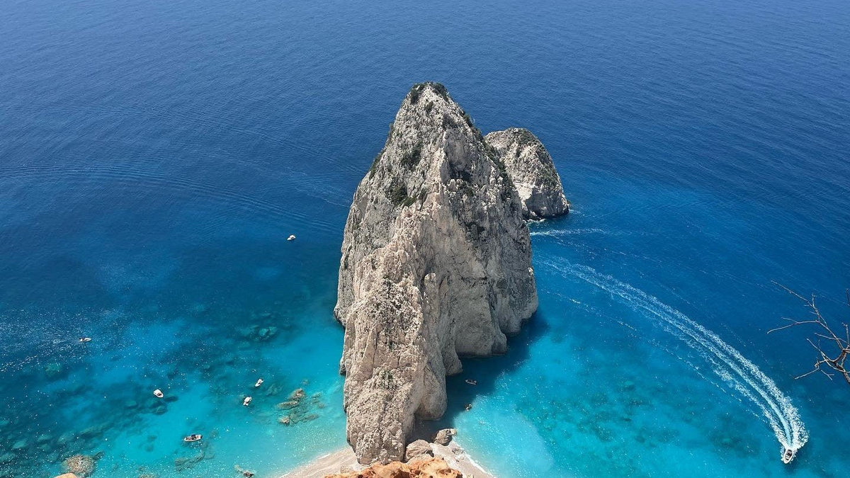 Limestone sea stacks rising out of clear turquoise water on the Zante coastline, where UK workers spend their days off during a Laganas season